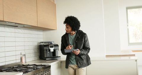 African american man checking modern kitchen cooktop with tablet and stylus