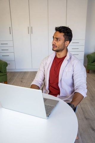 Focused man working at home office desk with laptop open