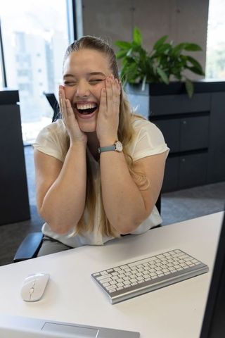 Joyful Woman Laughing at Modern Office Desk