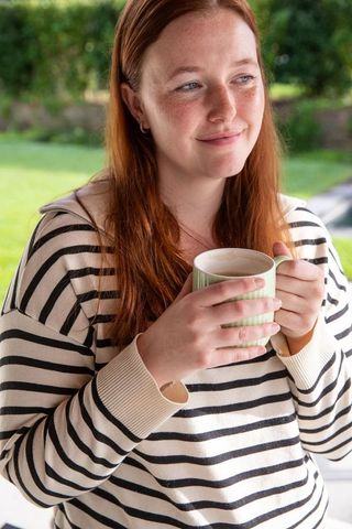 Woman with Red Hair Enjoying Drink on Sunny Patio