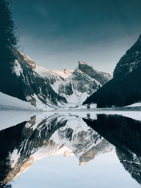 Majestic snow-capped mountains reflecting in calm lake, perfect for use in travel advertisements, nature photography, landscape calendars, desktop backgrounds, and relaxation-themed content.