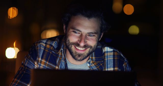 Man Smiling Working on Laptop at Night Under Warm Lighting - Download Free Stock Images Pikwizard.com