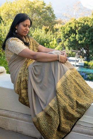 Elegant indian woman in traditional beige saree sitting outdoors