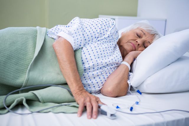 Elderly woman lying in hospital bed with a blanket and pillow, appearing restful and calm. Appropriate for use in healthcare materials, elder care promotions, and patient care facilities.