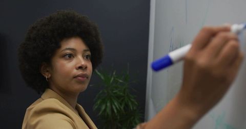 Professional woman writing on whiteboard in office setting