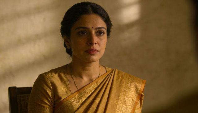 Contemplative indian woman wearing golden silk saree sitting in warm cinematic light
