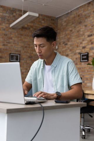 Focused professional man working on laptop in contemporary office