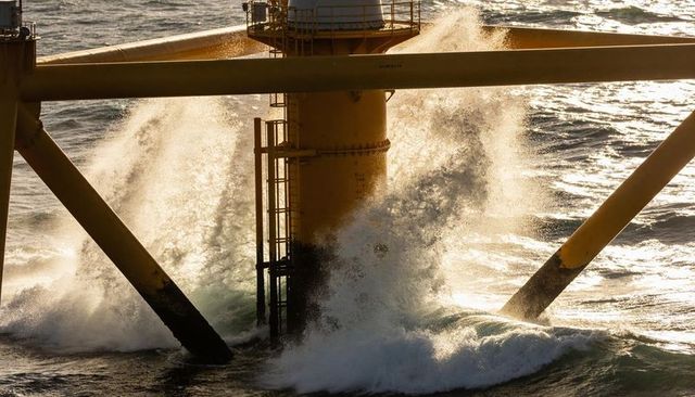 Offshore jacket leg taking heavy ocean waves at golden hour, steel platform