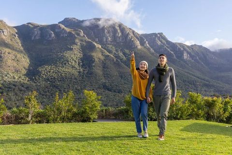 Couple walking hand in hand at mountain lookout pointing at scenic ridge