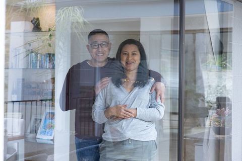 Smiling Senior Couple Relaxing at Home Behind Glass Door