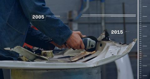 Worker grinding dented car panel with angle grinder producing sparks in metal workshop