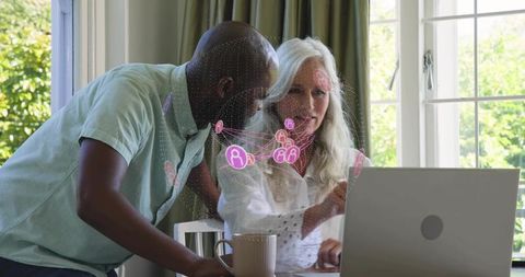 Mature couple collaborating on laptop at home with digital network visualization overlay