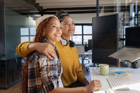 Diverse Female Coworkers Celebrating Success Together at Office Workspace