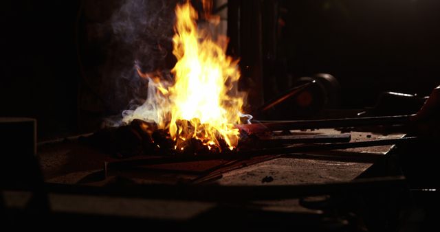 Hand of blacksmith heating iron rod in fire at workshop 4k