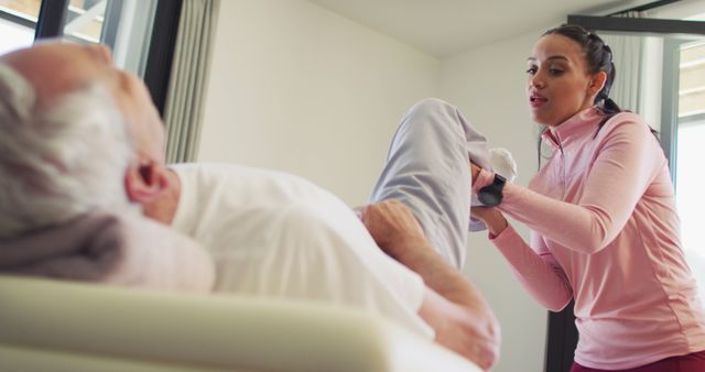 Young female physical therapist assisting an elderly man with exercise routine, indicating a focus on senior care and physical rehabilitation. This could be utilized in health care websites, brochures for assisted living facilities, or educational materials about elder fitness and recovery programs.