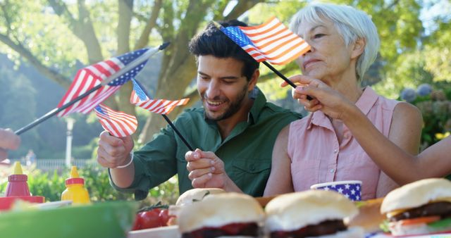 Family enjoying Fourth of July celebration outdoors. Ideal for use in advertising campaigns, social media posts about national holidays, and articles related to American traditions, family gatherings, and outdoor events. Highlights patriotism, unity, and festive spirit.