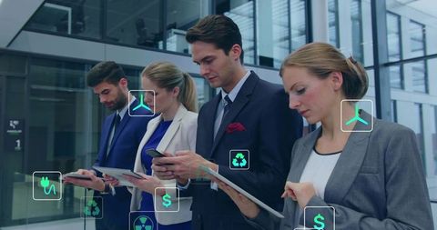 Business team using mobile devices with sustainability icons in modern glass atrium