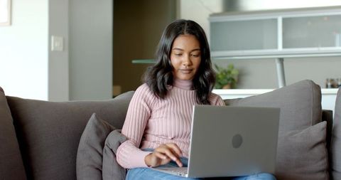 Asian Woman Working on Laptop in Cozy Home Lounge Setting