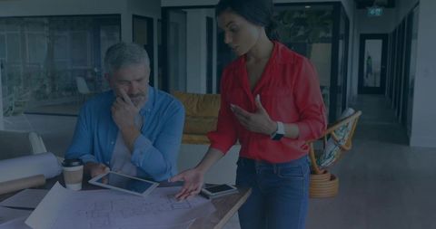Architects Reviewing Blueprints in Contemporary Office with Tablet