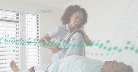 Female caregiver assisting senior man with leg rehabilitation in bedroom with teal overlay