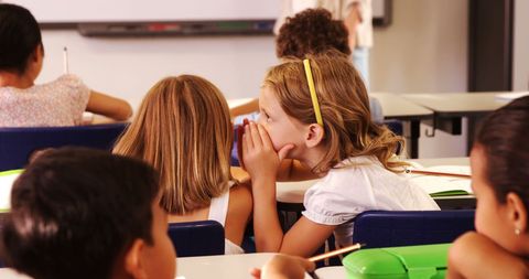 Children sharing secrets during class in educational setting