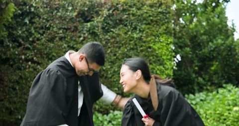 Joyful graduates celebrating outdoors with diploma