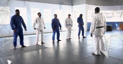 Black Belt Instructor Leading Jiu-Jitsu Class Demonstrating Technique on Bright Dojo Mats