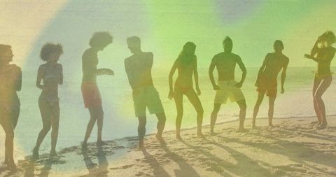 Group of Friends Dancing on Sandy Beach at Sunset