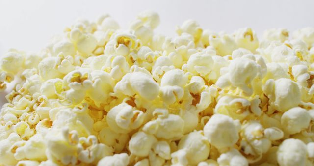 Popcorn falling against a white background creates a light and fun ambiance, perfect for showcasing the playful nature of cinema snacks. Ideal for use in marketing materials related to movies, home theater experiences, parties, and entertainment. The ample white space provides room for text or branding, making it versatile for promotional content.