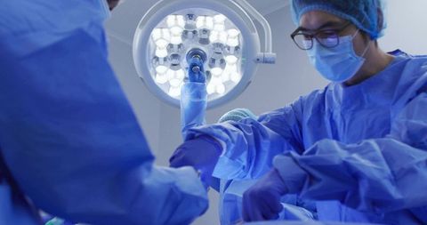 Surgical team preparing instruments under led operating light in hospital operating room