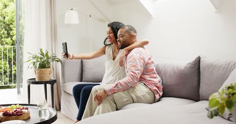 Cheerful Couple Taking Selfie on Comfortable Sofa at Home