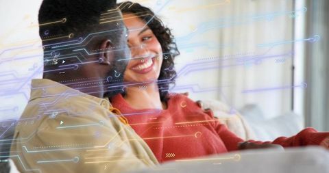 Smiling couple using tablet on sofa with digital circuit overlay showing smart technology