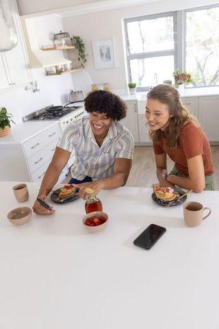 Couple enjoying sunny kitchen breakfast with pancakes, syrup and happy conversation