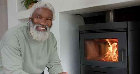 Senior man enjoying warmth of fireplace at home