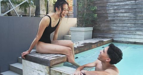 Couple enjoying private plunge pool, woman laughing on edge, man relaxing in water
