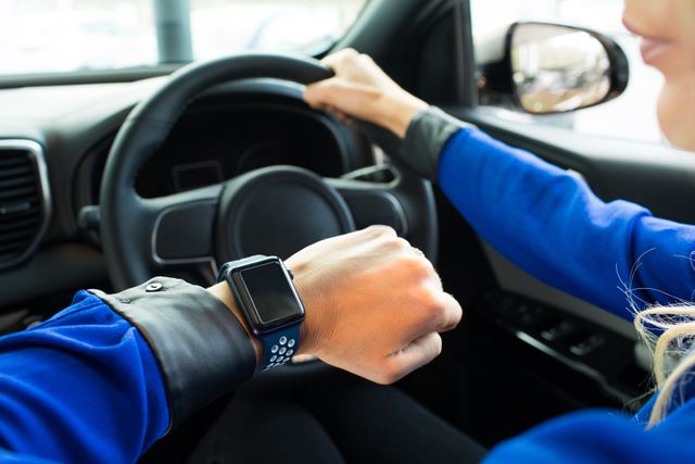 Cropped image of woman looking at smart watch during test drive in car