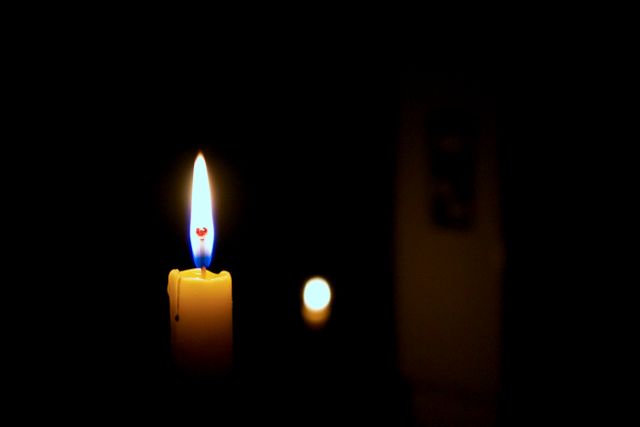 Picture of a burning candle with a single flame illuminating the dark surroundings, ideal for use in content related to peace, meditation, tranquility, spirituality, or themes of solitude and quiet moments.