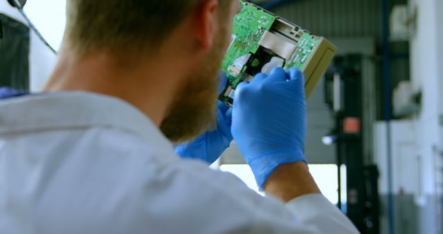 Close-up showing technician in lab coat repairing electronic device circuit, wearing blue gloves. Suitable for illustrating electronics repair, technology maintenance, engineering work environments and technical expertise.