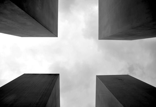 This abstract scene depicts four tall concrete slabs reaching towards a cloudy sky, creating a geometric aesthetic. Ideal for projects involving urban design, architecture, minimalism, or modern art. Can be used for editorial content, background imagery, design inspiration, or making a visual statement about modern cityscapes.