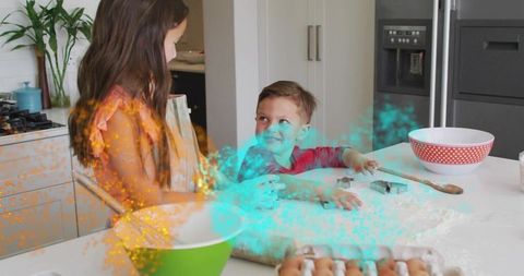 Playful siblings mixing dough in bright home kitchen surrounded by flour and cookie cutters