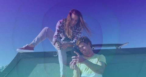 Youthful friends relaxing on skate ramp listening to music