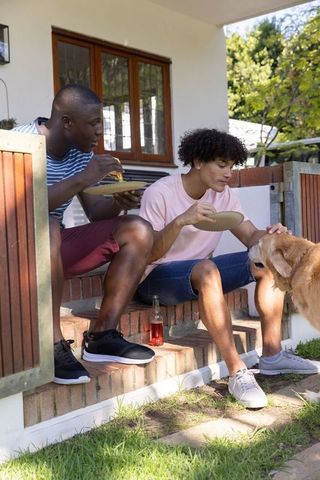 Friends enjoying pizza on porch with dog friendly vibes