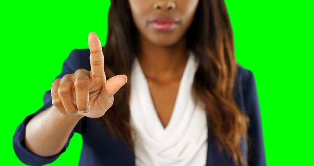 Young professional woman wearing business attire pointing at screen against a green background. Ideal for use in technology, business, and digital interaction themes, this image depicts modern work environments, presentations, and user interface designs.