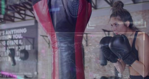 Female boxer training with heavy bag in industrial gym showing focus and intensity