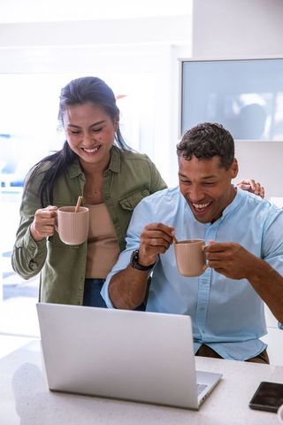 Happy Couple Laughing Together at Kitchen Counter with Laptop
