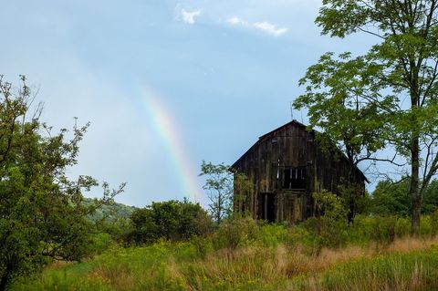 Rustic Barn Under Rainbow in Rural Summer Landscape
