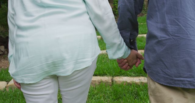 Senior Caucasian couple holding hands outdoors, with copy space. Their gesture symbolizes enduring companionship and support.
