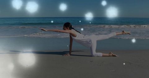 Chinese woman practicing yoga balance on serene beach with ocean waves and bokeh light