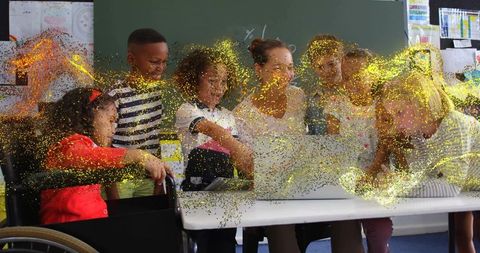 Teacher guiding diverse students around laptop, wheelchair inclusion, gold sparkle overlay