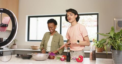 Diverse content creators filming vibrant home cooking tutorial at bright kitchen island